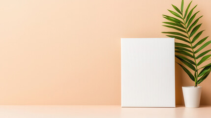 Blank canvas and potted plant on light peach background create serene and minimalistic atmosphere