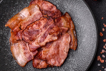 Cooked fried crispy bacon as an ingredient of a delicious English breakfast. Pieces of fried bacon