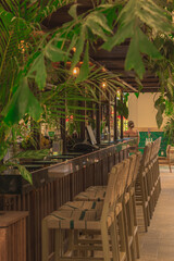 Tropical Bar Interior with Wooden Stools and Green Plants – Modern Resort Lounge