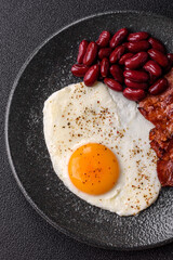 Fried egg, bacon and beans, a classic British breakfast with tomatoes. Egg, bacon and beans