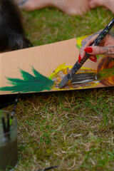 A person is actively painting on a piece of cardboard using a brush with vibrant colors and...