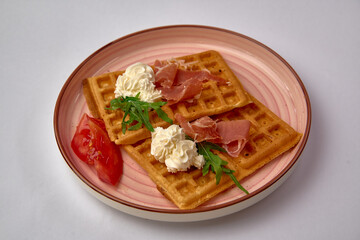 Deliciously Crafted Waffles Topped with Cream, Prosciutto, and Fresh Greens Served on a Decorative Plate for a Gourmet Experience