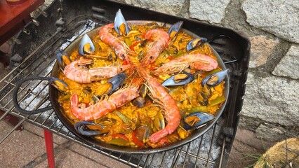 Traditional spanish paella with seafood on outdoor grill setting. Typical cuisine of Spain. Valencian cuisine. Stage of cooking paella. Ingredients for paella
