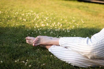 Man relaxing barefoot on grass wearing striped loose pants in garden