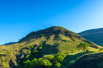 Beautiful view of the slope of a green mountain in the rays of the morning sun. Caucasus