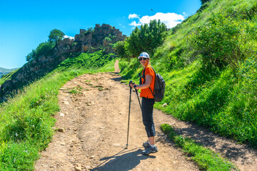 A female tourist with trekking poles on a ramp going to the mountain ghost town of Gamsutl. Caucasus