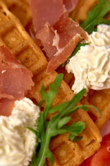 Deliciously Crafted Waffles Topped with Creamy Whipped Topping, Curled Ham Slices, and Fresh Arugula, Perfect for a Savory Breakfast Delight