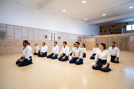 Multiethnic martial arts class meditating in seiza position in the dojo