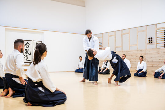 Sensei performing martial arts throw during aikido practice in dojo - Powered by Adobe
