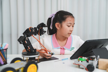 A young girl using a tablet to program a robotic arm.