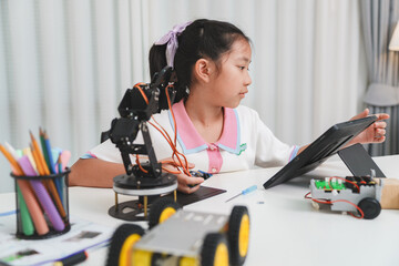 Young girl building a DIY robot with digital instructions on a tablet.