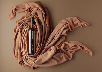 Bottle of white wine against a background of draped beige and brown fabric.