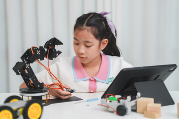 Asian girl using a touch screen tablet to program her robot.
