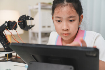 A young girl focused on her tablet during an online robotics class.