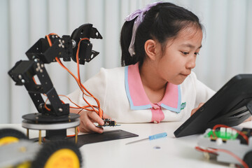 A girl programs a robot with a tablet. Engineering, technology, and learning.
