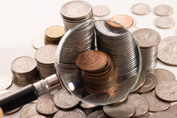 Through magnifying glass the coin as a small group other coins of various advantage lie is visible