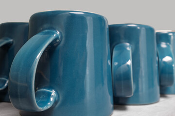 Several blue teal ceramic mugs turned upside down in a neat row on a kitchen countertop. Ideal for...