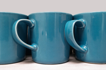 Upright blue ceramic mugs arranged side by side on a light-colored kitchen countertop. Captures clean, minimal, and domestic aesthetic