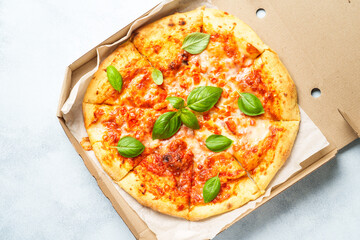 Pizza Margarita in a cardboard box on white background.