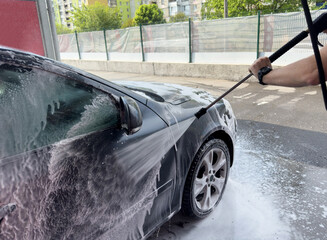 Closeup of male driver washing his car with contactless high pressure water jet