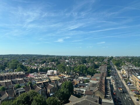 aerial view of North Finchley looking south towards Golders Green and central London along Ballards Lane N12. Blue sky, Green trees, roof tops and a building site clearly visible from above. - Powered by Adobe