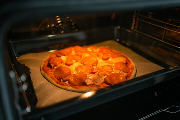 Pepperoni pizza baking in a hot oven on a baking sheet, with melted cheese and rich tomato sauce...