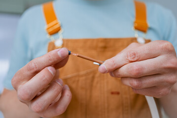 Professional electrician carefully removing wire insulation while installing electric stove,...