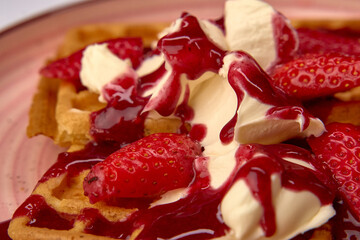 Delicious Homemade Waffles Topped with Fresh Strawberries and Cream, Drizzled with Rich Strawberry Sauce for a Perfect Dessert Experience