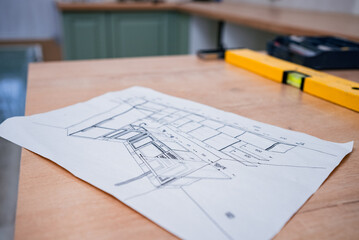 Sketch of kitchen furniture lying on a table, accompanied by a spirit level, highlighting the process of assembling a new kitchen project during home renovation efforts