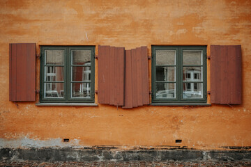 Des fenêtres vertes sur un mur orange dans une petite rue