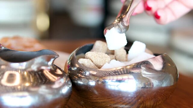 White granulated sugar in spoon in the background pile sugar cubes, top view, close up, rotates. The concept of unhealthy eating, obesity, heart disease, diabetes