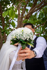 Cropped shot of an unrecognizable bride and groom standing together and holding flower Bouquet.