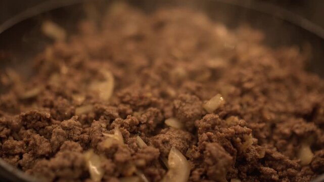 Fresh ground beef sizzling in a pan with rich seasoning, steam rising from perfectly browned meat. Appetizing texture and golden crust, ideal for tacos, pasta, or homemade dishes.