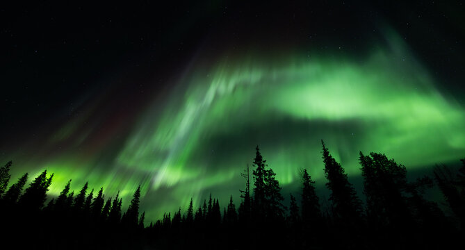 Northern lights, aurora borealis in the night sky over frozen lake in Lapland, Finland