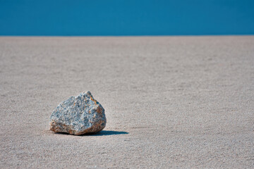 photorealistic ultraminimalistic scene featuring solitary stone resting on clean sandy background