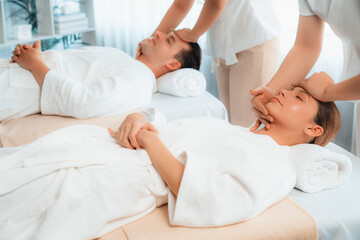 Obraz premium Caucasian couple enjoying relaxing anti-stress head massage and pampering facial beauty skin recreation leisure in dayspa modern light ambient at luxury resort or hotel spa salon. Quiescent