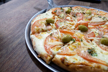 An Argentine Neapolitan pizza sliced on a table