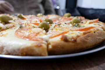 A sliced Argentinian Neapolitan pizza photographed close up with various parts blurred - natural light