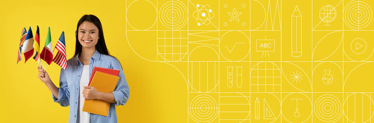 Asian student smiles confidently while holding flags representing different countries. She stands against a vibrant yellow background, showcasing her dedication to education