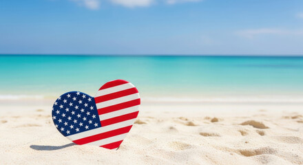 Heart shaped american flag decoration resting on a sandy beach with turquoise ocean and blue sky