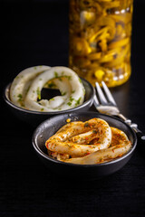 Marinated squid rings in bowl on black table.
