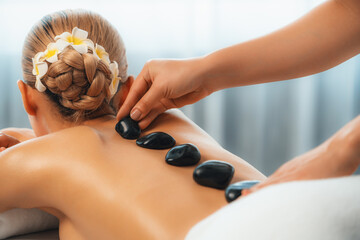 Hot stone massage at spa salon in luxury resort with day light serenity ambient, blissful woman...