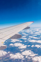 Obraz premium View from the airplane window at a beautiful cloudy sky and the airplane wing