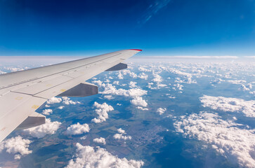 View from the airplane window at a beautiful cloudy sky and the airplane wing