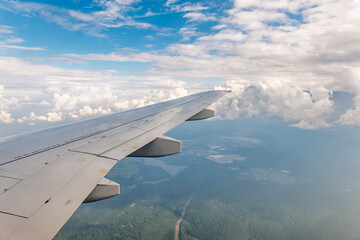 Obraz premium View from the airplane window at a beautiful cloudy sky and the airplane wing