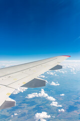 Fototapeta premium View from the airplane window at a beautiful cloudy sky and the airplane wing