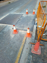 Workers laying plastic pipes for sewerage and communications on the street with red protective caps and grating
