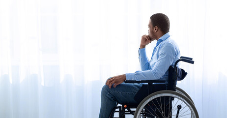 Disability and depression. Side view of young black man in wheelchair shutting himself off from...