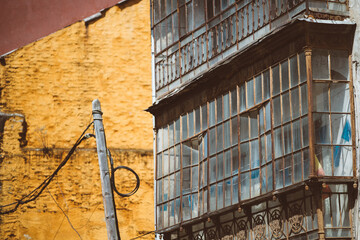 Textured urban study of Tineo, Spain: weathered iron and glass enclosed balcony with cracked panes...