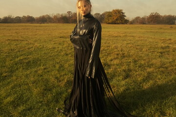 Beautiful girl in the garden on a sunny day. Black dress. Summer nature, old tree